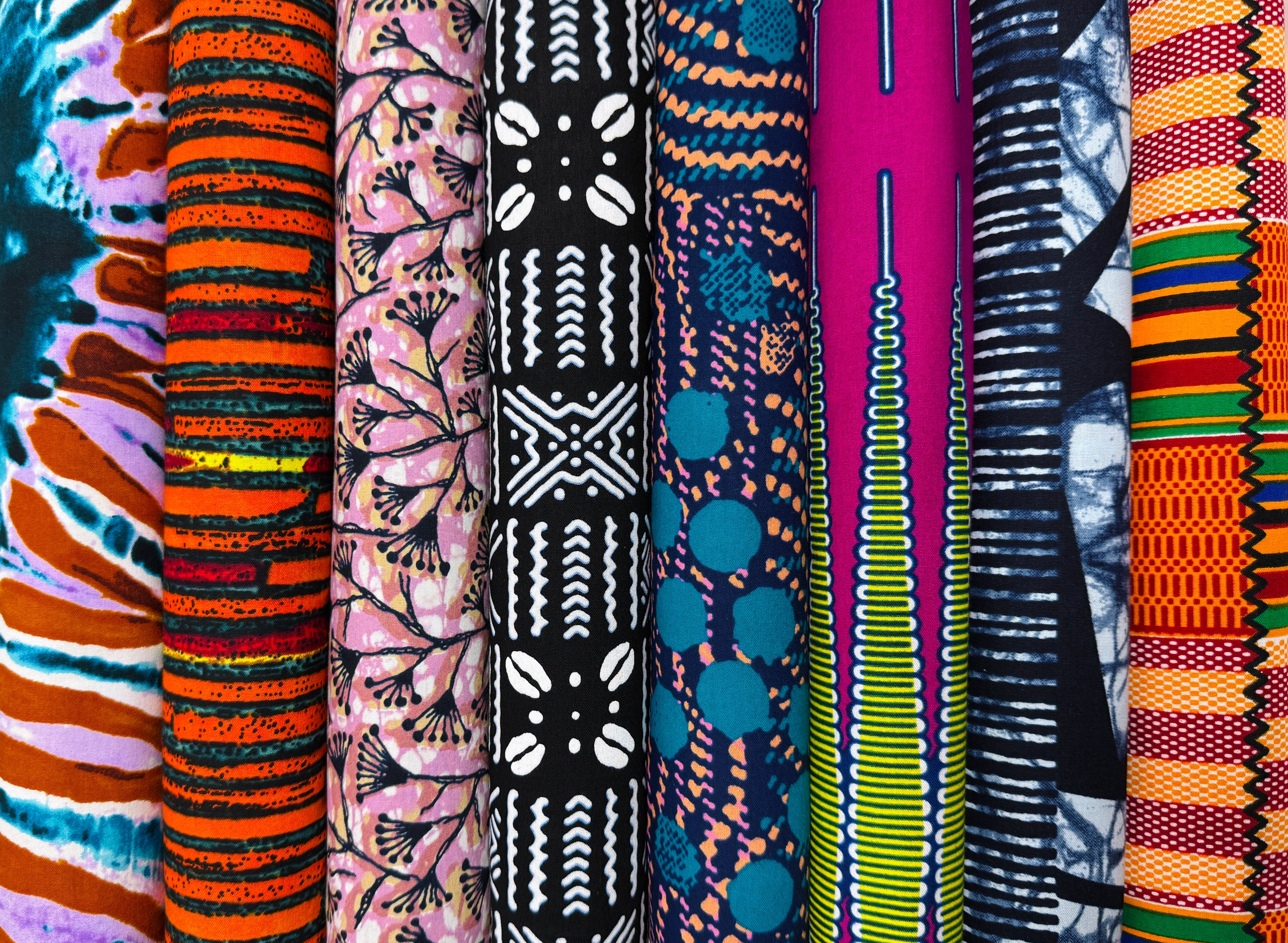 A curated collection of African fabrics featuring vibrant Ankara wax prints, Kente-inspired motifs, and bold tribal geometric patterns, showcasing West African textile heritage.