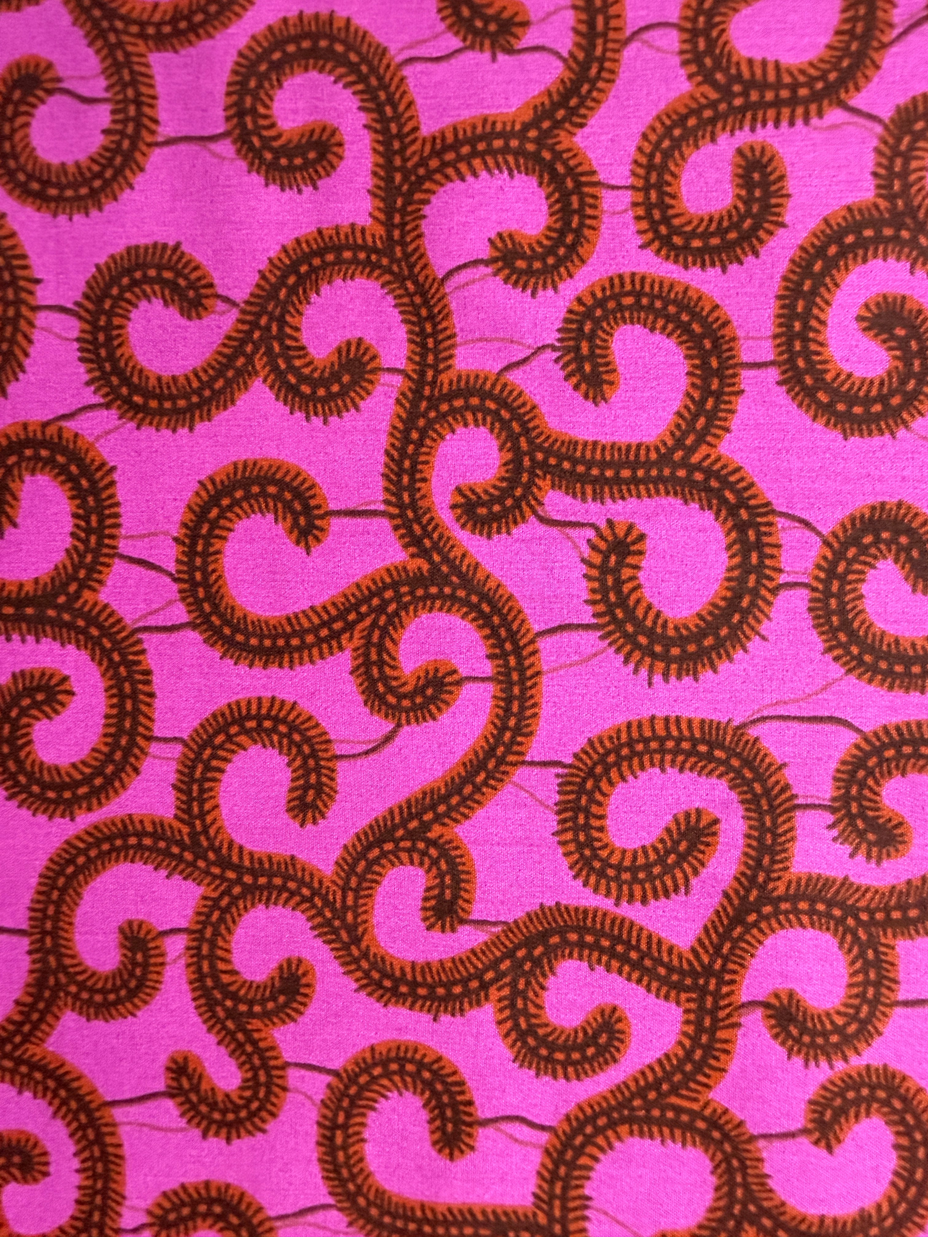 Brown swirling pattern on a pink fabric background