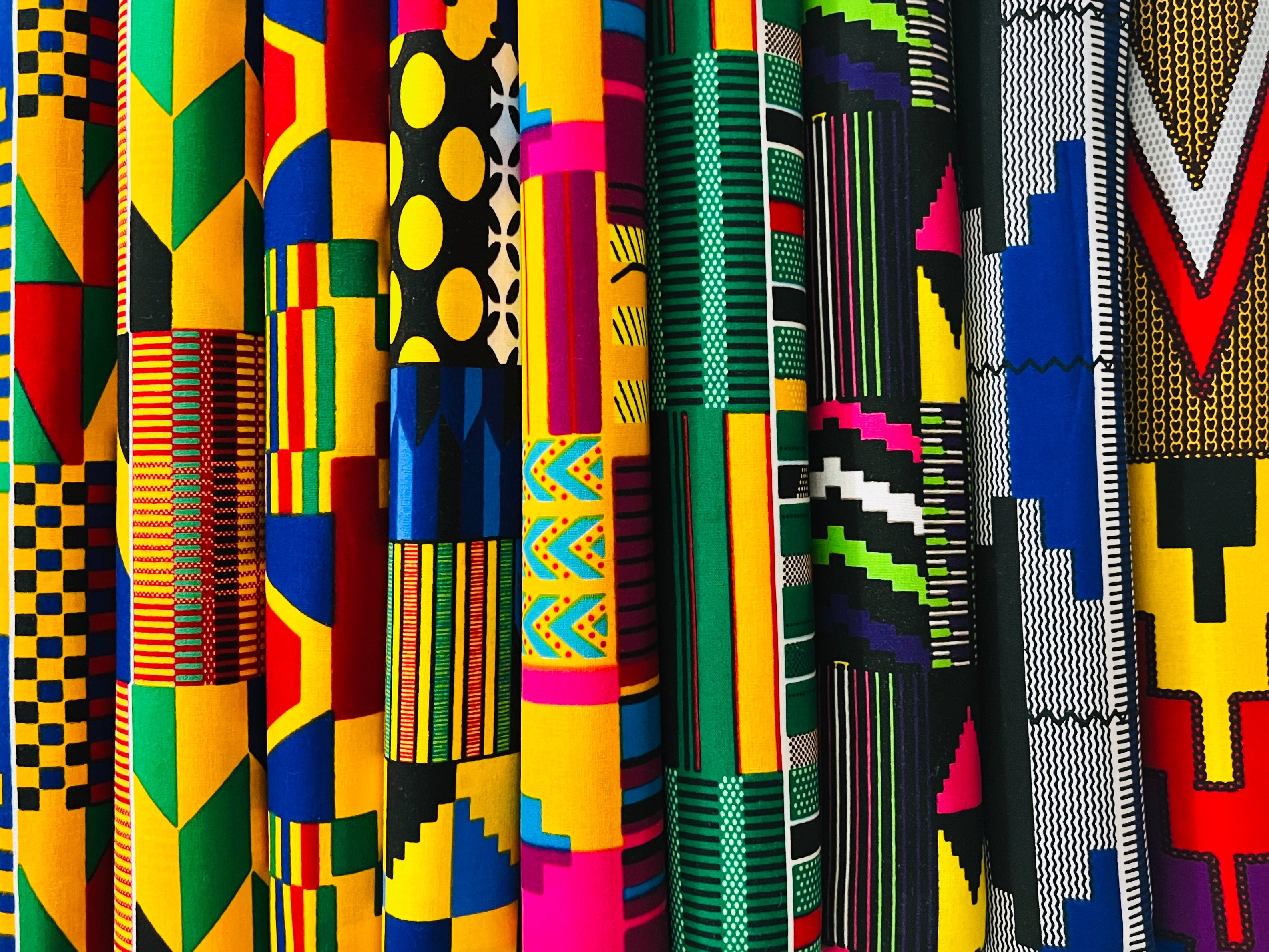 Kente-inspired African print fabrics in vibrant geometric patterns, available by the yard, fat quarters, and scrap bundles